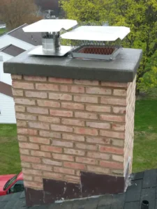 A freshly repaired brick chimney with metal flue caps on a rooftop